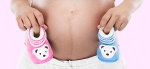 Une femme enceinte heureuse tenant son ventre rond, annonçant la naissance prochaine d'un garçon ou d'une fille.